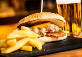 A sandwich and fries on a table with a glass of beer.